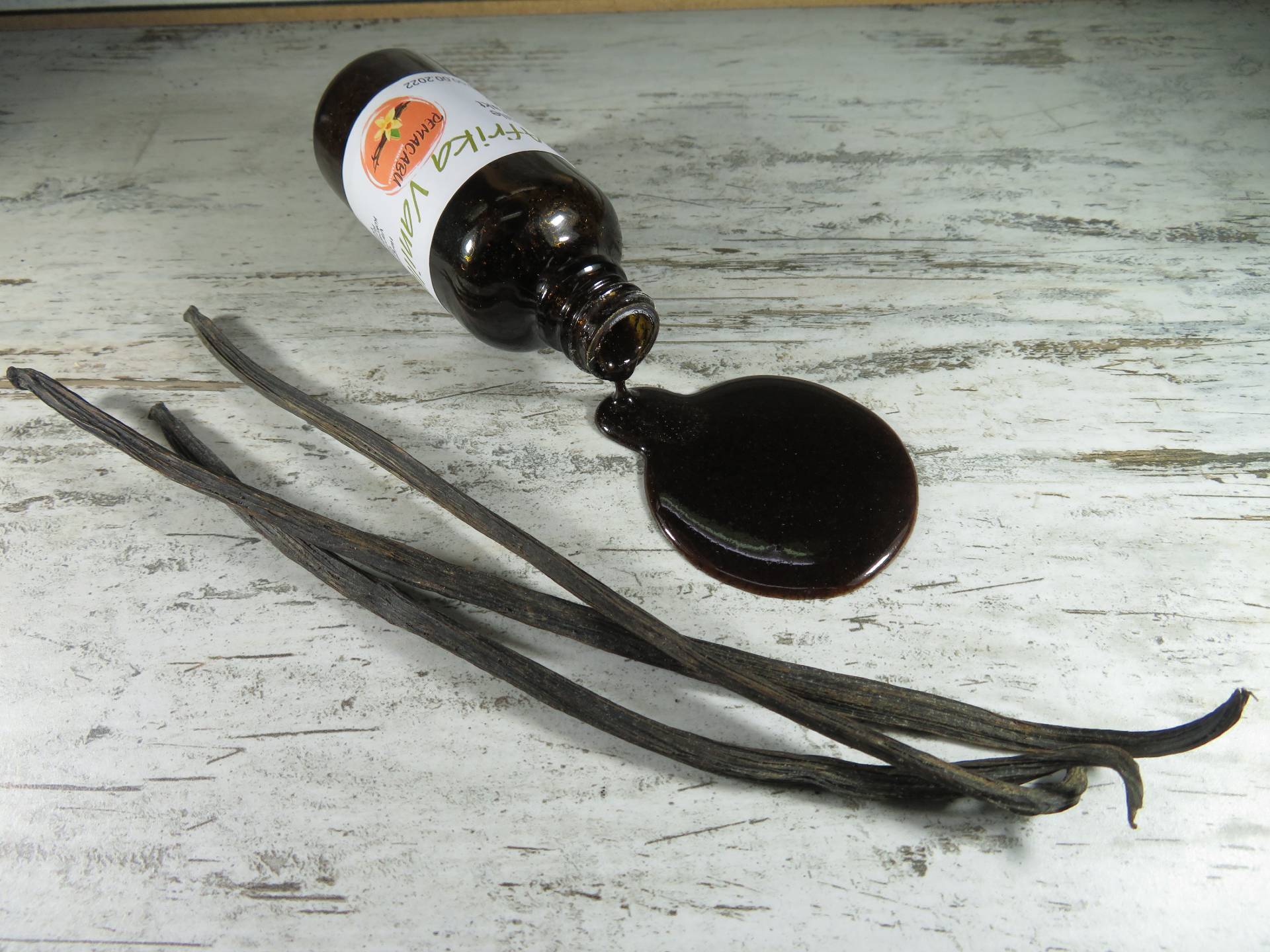 Vanilleextrakt neben Vanilleschoten